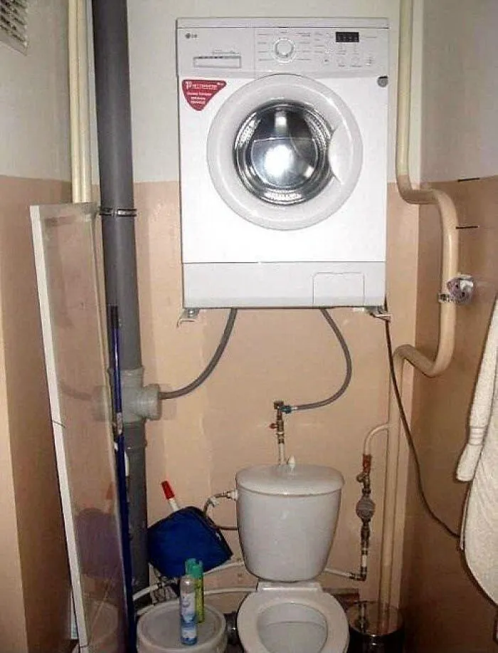A washing machine mounted dangerously on the wall above a toilet, showcasing an attempt to renovate their homes.