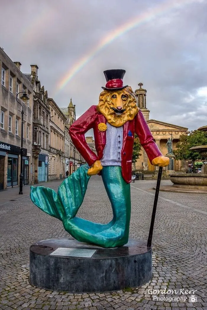 A colorful statue of a dapper lion-headed merman with a cane and top hat, showcasing unique public art