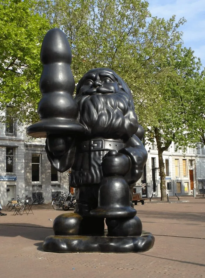 A bizarre public art sculpture of Santa Claus holding a controversial toy-shaped object in a city square