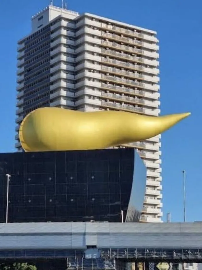 A gold flame monument showing unusual public art on top of a modern building