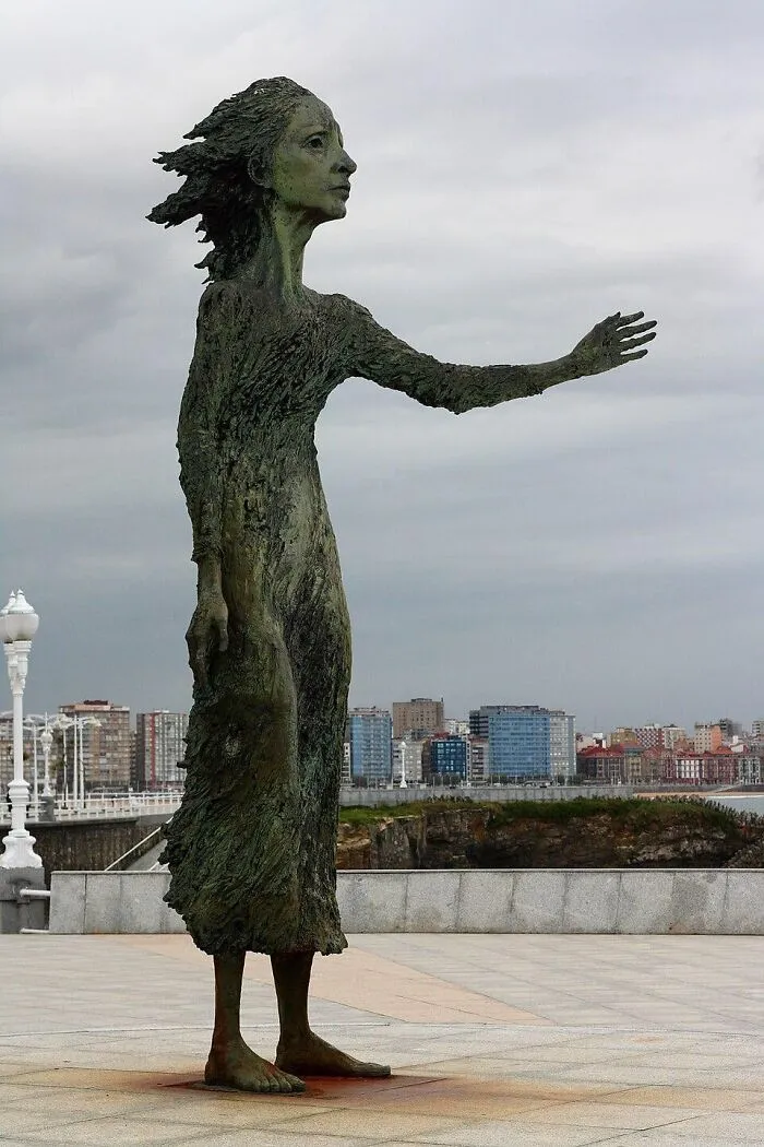 A bronze statue of a woman with her arm outstretched, representing examples of public art by the sea