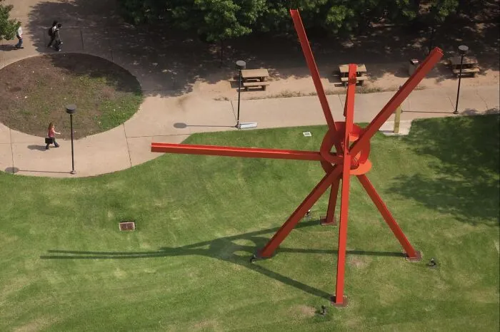 An abstract red steel structure on a grassy lawn, representing examples of public art