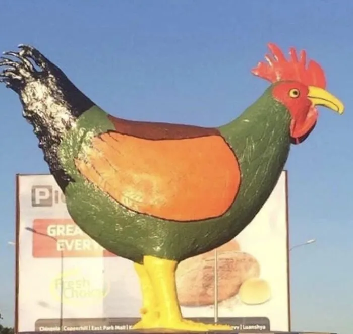 A poorly painted and bizarre chicken statue standing outdoors as an example of bad public art