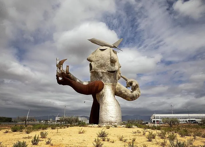 A giant, abstract metallic head statue in a field, a famous and bizarre piece of public art.