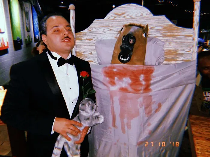 Two people in a creative Godfather-inspired Halloween costume featuring a horse head in bed.