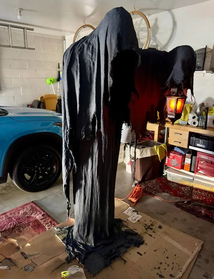 A life-sized hooded figure holding a lantern for Halloween homes theme.