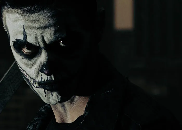 Terrifying makeup on haunted house worker in dark setting