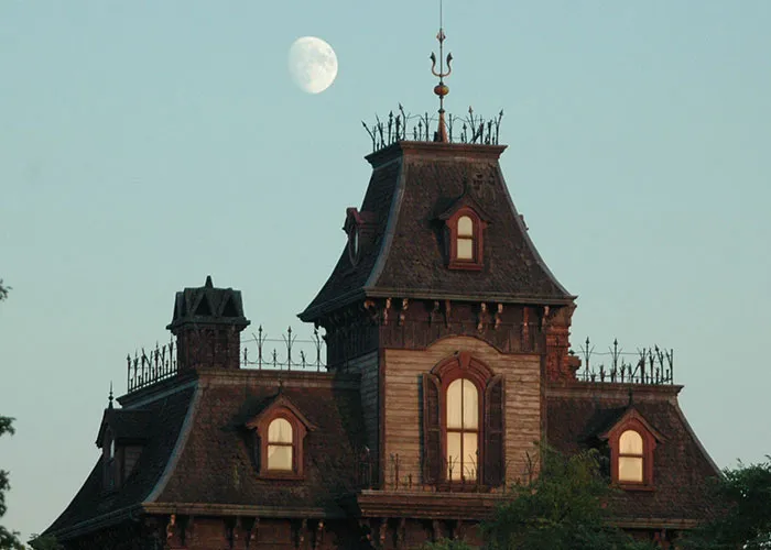 Creepy haunted house silhouette with moon in background