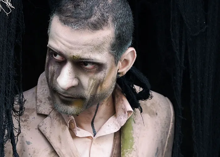 Haunted house worker with spooky zombie face paint and costume