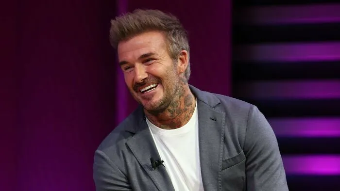 Man smiling during interview on purple background with casual blazer