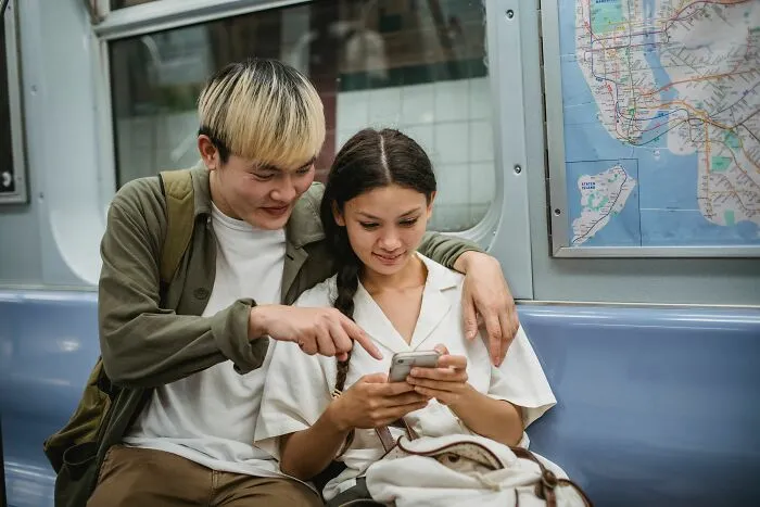 Couple looking at phone together on subway train