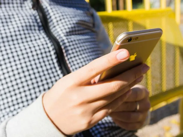 Person holding and using a smartphone outdoors with a blurred background
