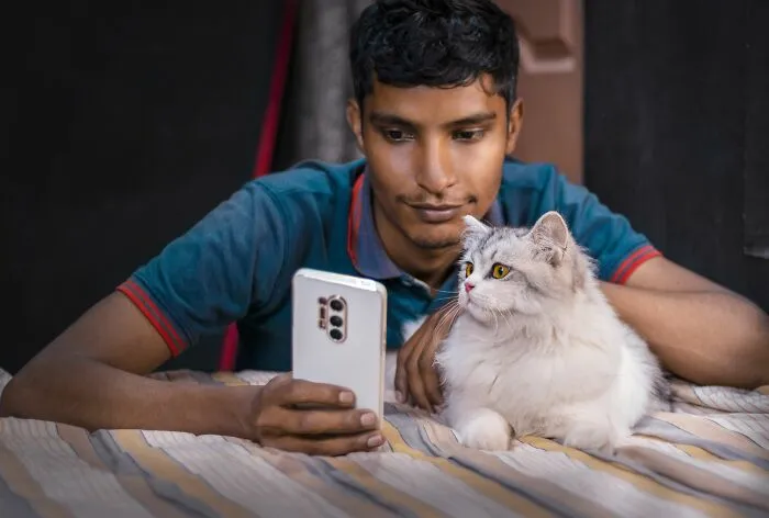 Man with smartphone and white cat lying on bed illustrating unexpected BF phone finds