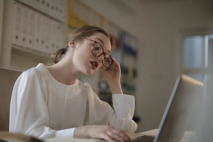 A stressed woman looks at her laptop, showing people behaving like they are owed everything in the office
