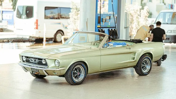 Vintage green convertible car parked at a gas station, reflecting on people behaving like the world owed them everything