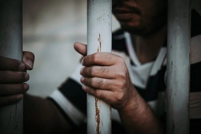 Hands gripping metal bars from inside a cell, highlighting how everything can fall apart.