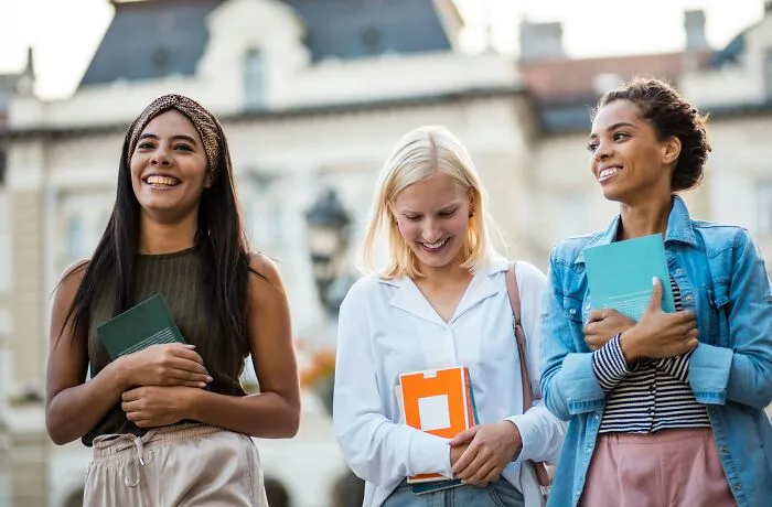 Three young female students holding books outdoors, representing sobering stories of life decisions