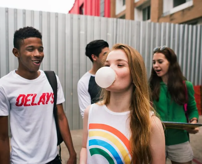 Young girl blowing a bubble gum bubble near friends showing how quickly everything can fall apart unexpectedly