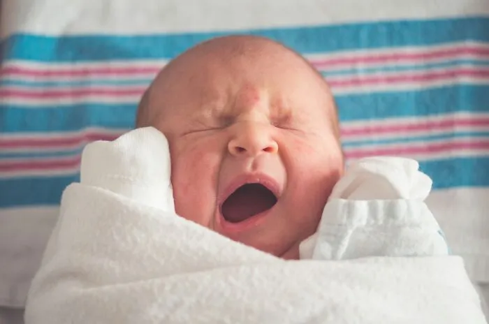 Newborn baby wrapped in a swaddle blanket yawning, illustrating sobering stories of life changing moments