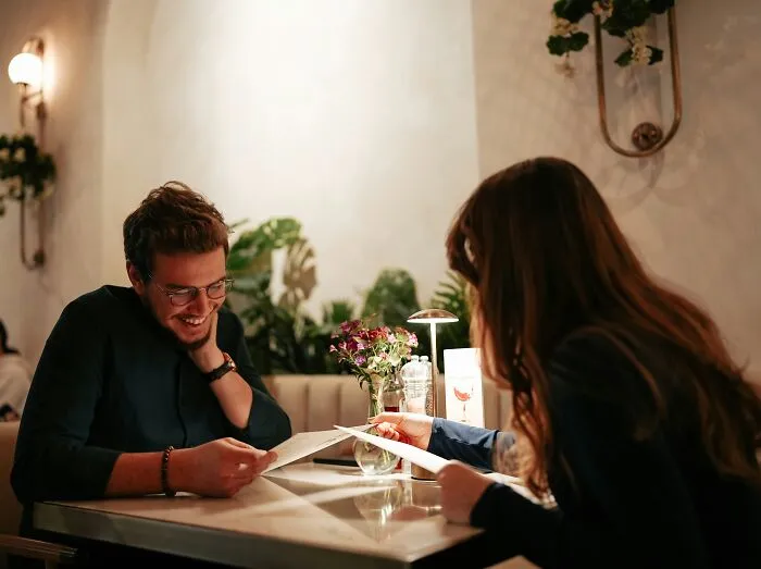 A happy couple looking at menus in a cozy restaurant during a date night.