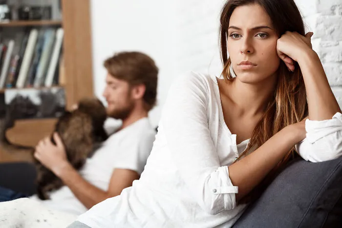 An upset woman sitting near a man with a dog, depicting sobering stories of relationship breakdowns.