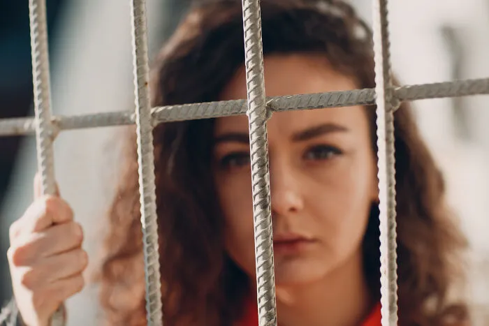 A woman looking through metal bars, reflecting sobering stories of sudden life choices.