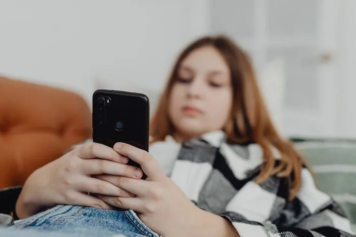 A young person holding a smartphone, illustrating sobering stories of instant online mistakes.