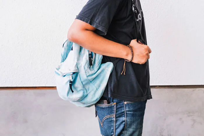 Side view of a student carrying a light blue backpack, symbolizing sober stories.