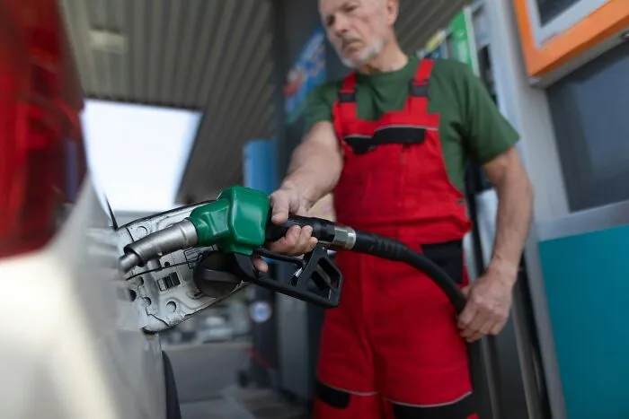 A gas station worker refueling a car, tied to sobering stories of costly everyday errors.