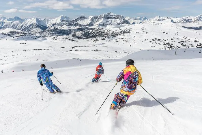 Skiers descending a snowy mountain, representing sobering stories of sudden outdoor accidents.