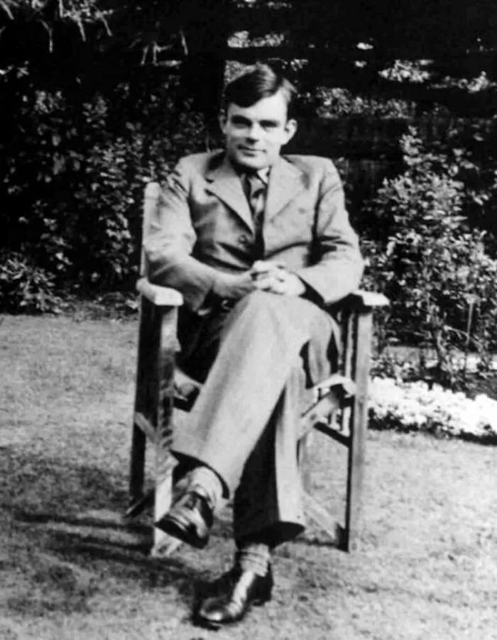 Black and white photo of man sitting on chair outdoors in formal attire