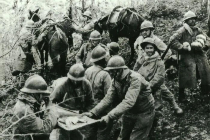 Black and white photo of soldiers carrying an injured comrade through forest