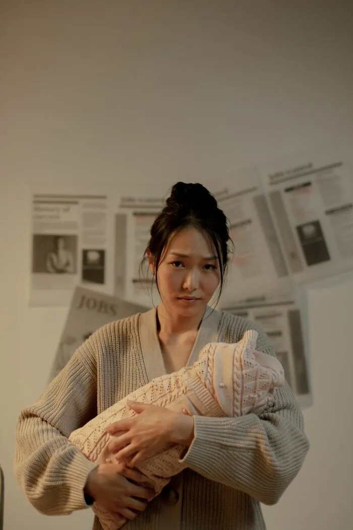 Woman holding baby with worried expression and newspaper background