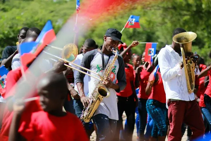 Group of people celebrating with brass instruments and waving flags