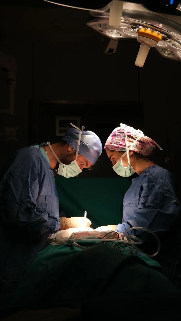 Surgeons performing operation in a darkened operating room under surgical light