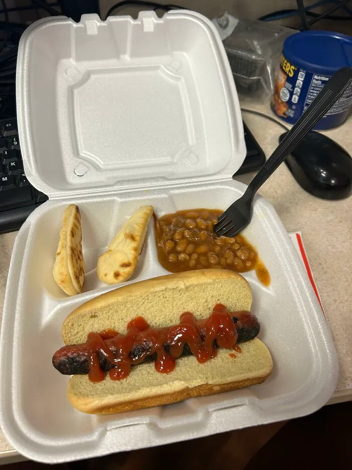 A meager hot dog and baked beans meal served in a takeaway container as bad employee bonuses.