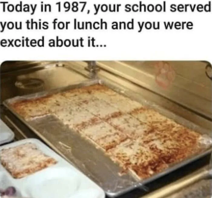 Tray of rectangular school cafeteria pizza from 1987, evoking '80s kids memories.