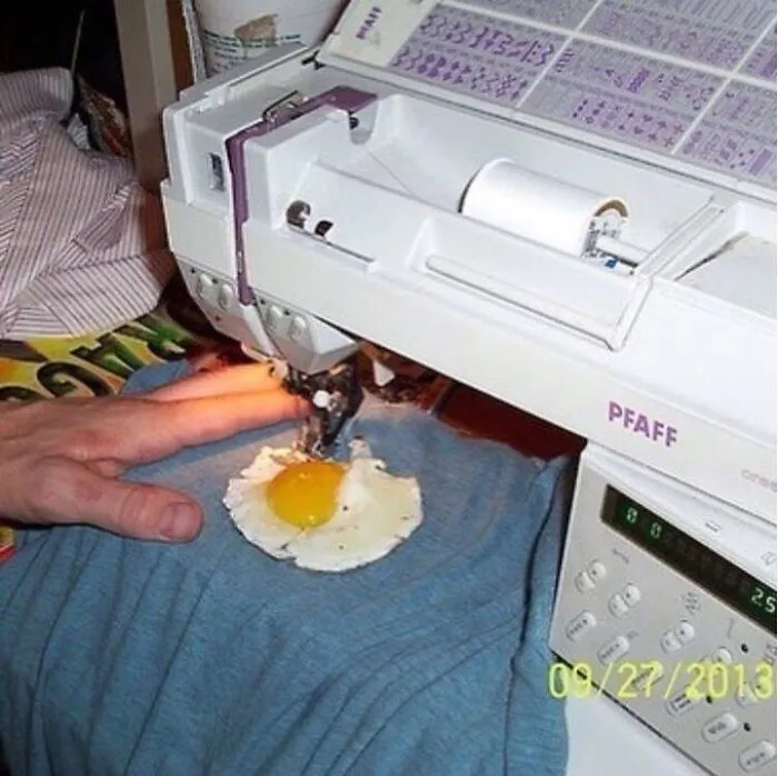 Sewing machine stitching a fried egg on blue fabric in a strange cursed image