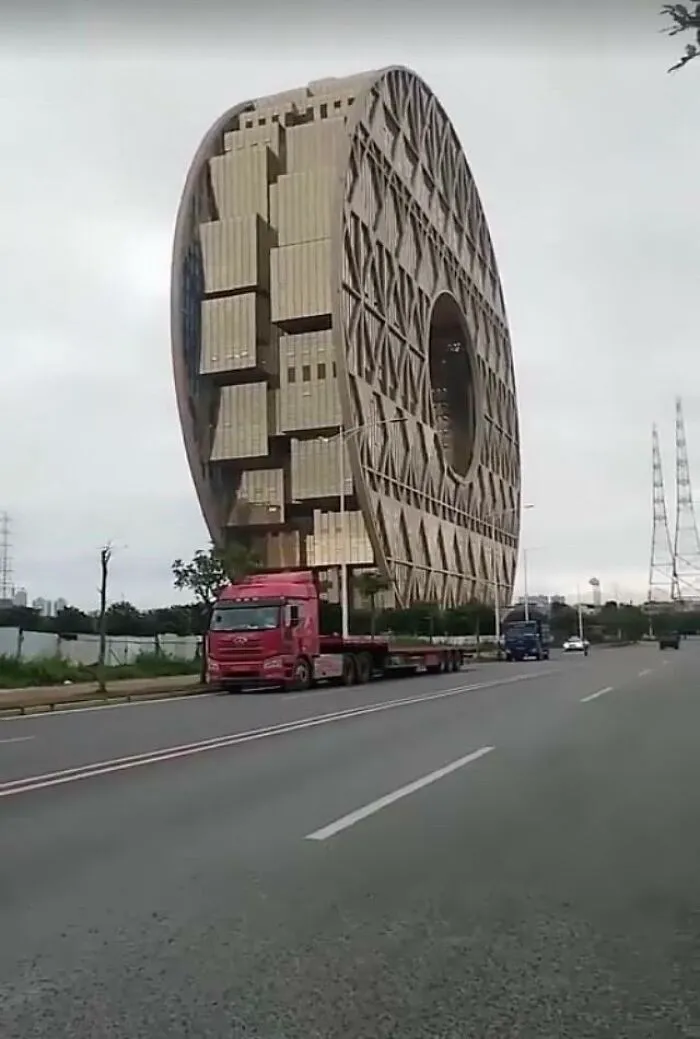 A red truck parked in front of a giant circular modern building, creating one of many perfectly confusing photos.