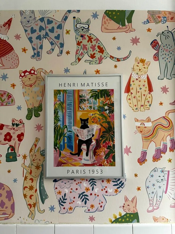 Cat themed bathroom home makeover showing playful cat wallpaper and a framed cat poster