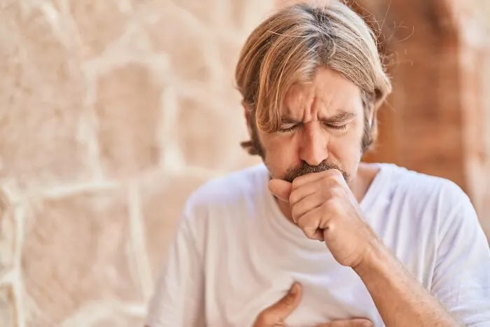 Man coughing and clutching chest depicting health reactions