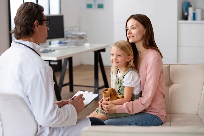 A doctor talking to a mother and child in a medical office, listening to their story.