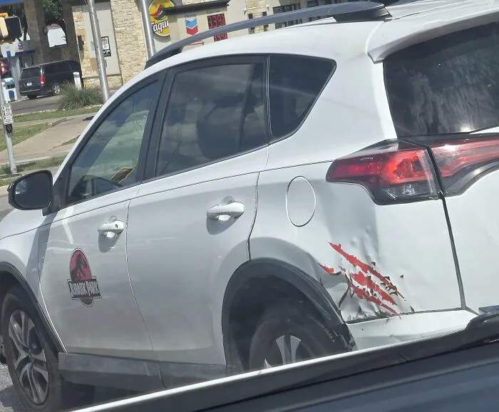 A white car with Jurassic Park logo and claw mark decals covering real damage as one of many absurd products.