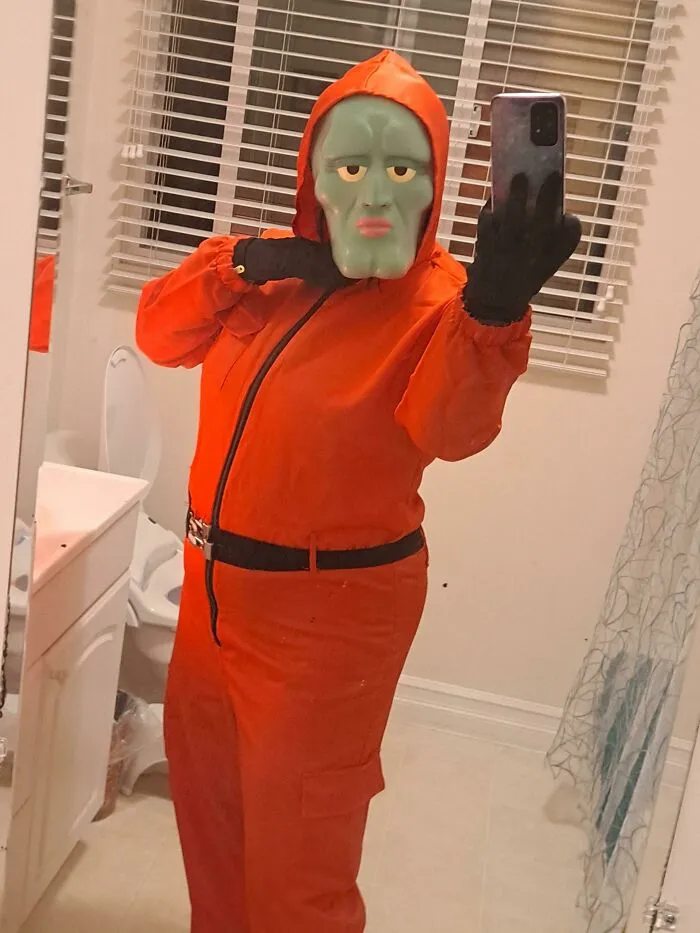 A person dressed in a red jumpsuit with a Squid Game mask, showcasing a creative Halloween costume idea.