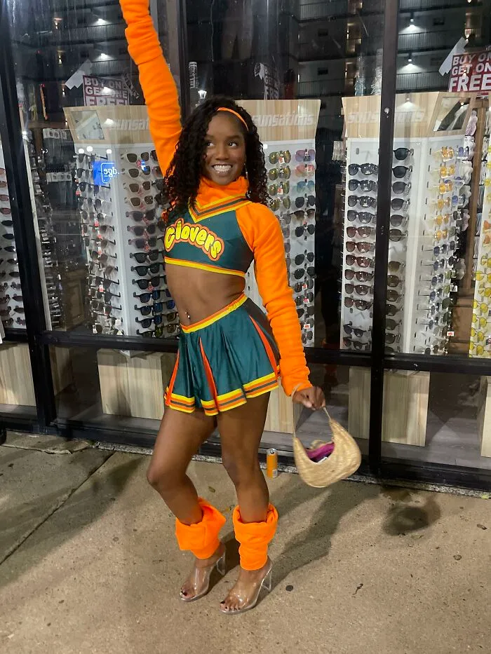 Woman in a green and orange cheerleading uniform posing, showcasing creative Halloween costume ideas.