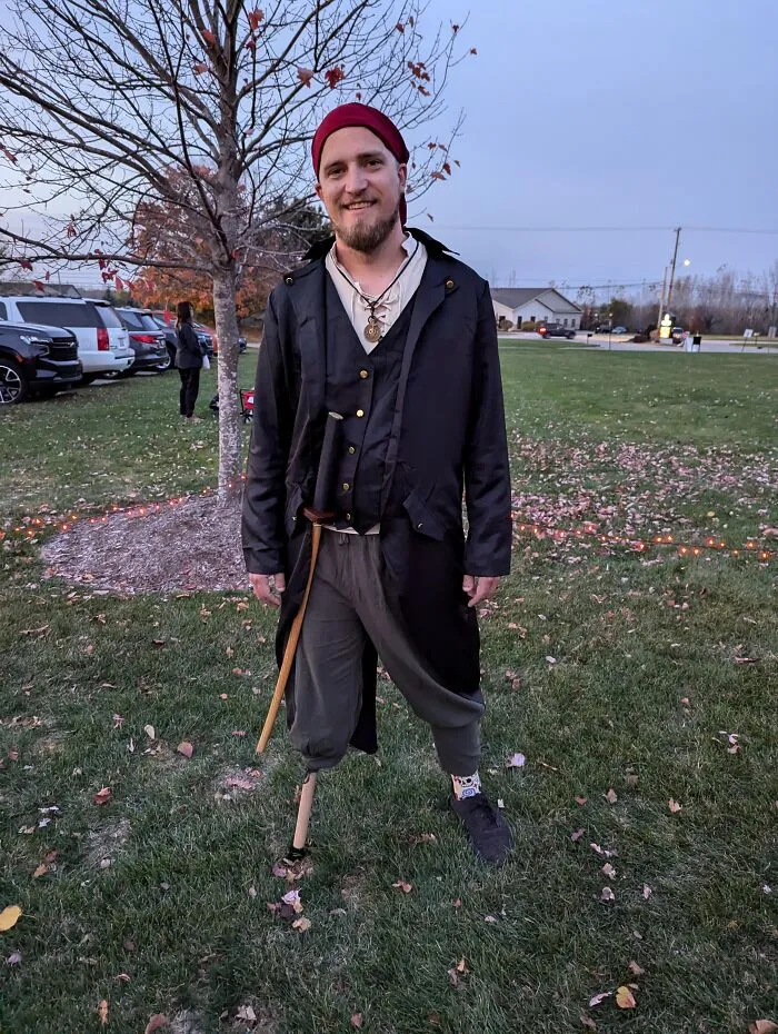 A man dressed as a pirate with a wooden peg leg, among creative people with disabilities celebrating Halloween.