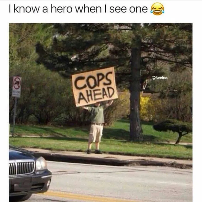 Funny rednecks meme showing a person holding up a hand-painted COPS AHEAD sign near a road.