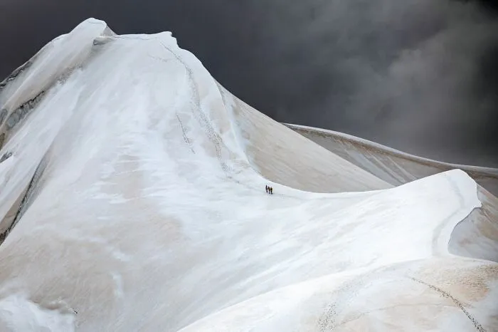 Two climbers on a snowy mountain ridge under dark sky best pics 2026