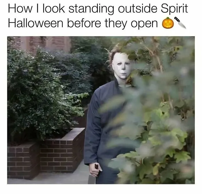 Spooky season meme featuring Michael Myers standing outside behind bushes holding a knife.