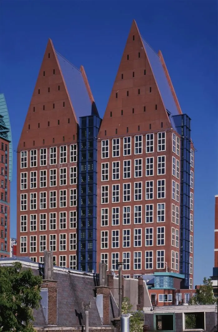 Building with steeply pitched red roofs and grid-like window pattern under clear blue sky